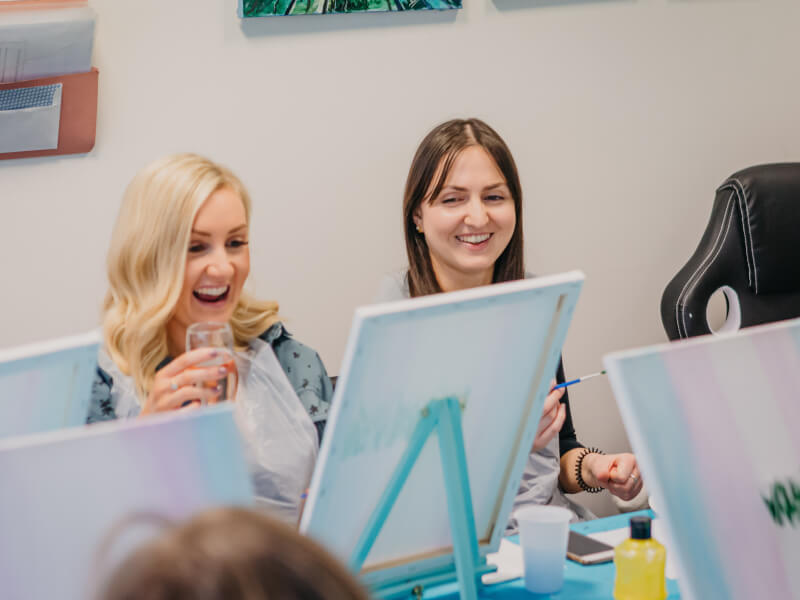 A group of ladies chat paint and drink.